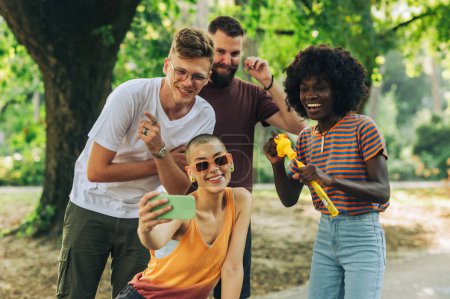 Eine kleine interrassische Gruppe von Influencern, die sich im Park vergnügen und Selfies machen. Junge multikulturelle Menschen feiern das Miteinander und die Einheit in der Natur. Porträt junger Leute, die Selfies im Park machen.