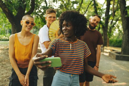 Porträt multikultureller Studenten, die während einer Pause Selfies auf dem Campus machen. Austauschschüler amüsieren sich gemeinsam im Park und machen Selfies. Influencer live streamen und Selfies im Park machen.