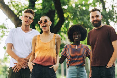 Porträt einer trendigen multirassischen Gruppe von Freunden, die in einem Stadtpark steht und in die Kamera lächelt. Eine kleine Gruppe von Freunden posiert und lächelt in die Kamera. Wahre Freundschaft.