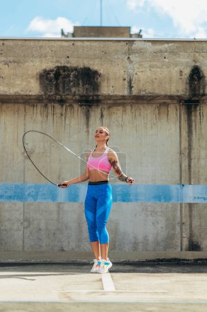 Attractive young woman using a fitness jump rope while training outside in an urban environment
