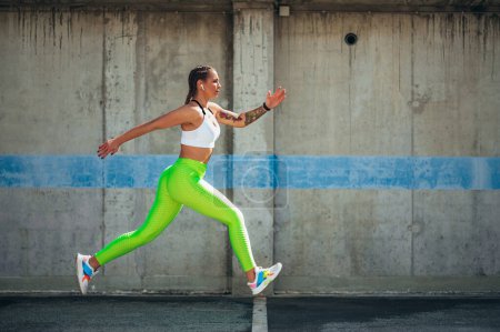 Attractive young woman running while training outside in an urban environment