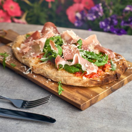 Photo for Fresh baked focaccia or pizza with prosciutto crudo and arugula. selective focu. romana's pizza. - Royalty Free Image