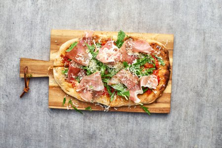 Photo for Fresh baked focaccia or pizza with prosciutto crudo and arugula. selective focu. romana's pizza. - Royalty Free Image