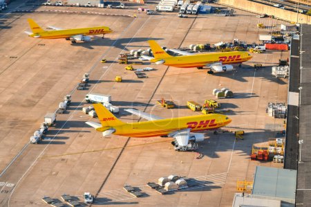 Photo for London, England - August 2022: Aerial view of cargo planes operated by DHL parked for unloading at the cargo terminal of an airport. - Royalty Free Image