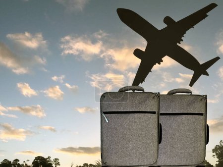 Foto de Dos maletas de viaje al aire libre con la silueta de un avión de pasajeros volando por encima. Concepto de viaje. No hay gente. Copiar espacio. - Imagen libre de derechos