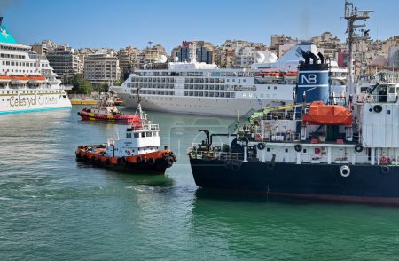 Foto de Pireo, Atenas, Grecia - junio de 2022: Pequeño remolcador que escolta a un buque petrolero utilizado para repostar buques más grandes en el puerto del Pireo. - Imagen libre de derechos