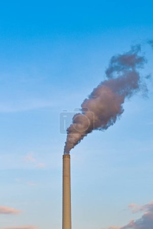 Photo for Smoke belching out of a tall chimney stack at a power station. No people. Copy space. - Royalty Free Image