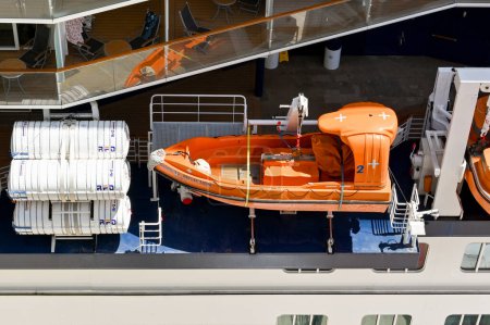 Photo for Kusadasi, Turkey - May 2022: Ariel view of a fast emergency speedboat stored on the side of a cruise ship alongside containers holding life rafts - Royalty Free Image
