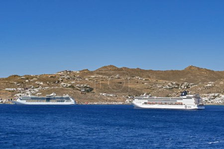 Foto de Mykonos, Grecia - Junio 2022: Crucero MSC Armonia fondeado frente a la costa de la isla griega de Mykonos con otro transatlántico - Imagen libre de derechos