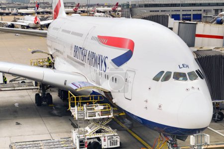 Foto de Londres, Reino Unido - febrero de 2023: British Airways Airbus A380 jet (matrícula G-XLEH) en una terminal del aeropuerto con un vehículo de carga de paletas junto a la puerta abierta de la bodega de carga - Imagen libre de derechos