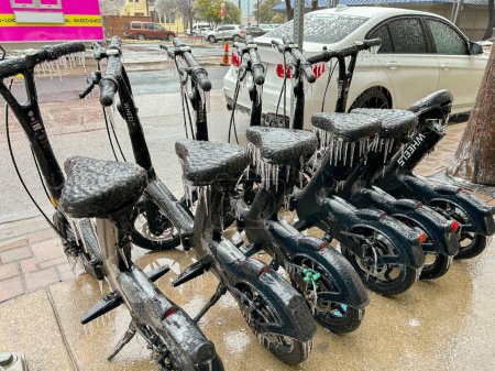Foto de Austin, Texas, EE.UU. - Febrero 2023: Fila de bicicletas eléctricas de alquiler cubiertas de hielo y carámbanos después del clima extremo - Imagen libre de derechos