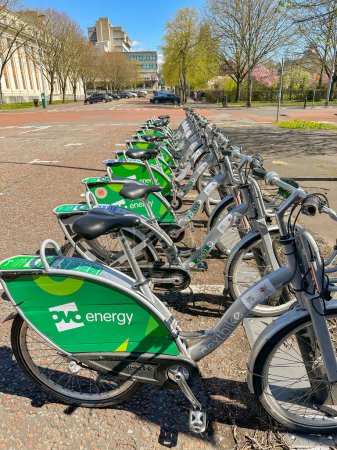 Foto de Cardiff, Gales - Abril 2023: Fila de bicicletas estacionadas en un rack como parte de un sistema de intercambio de bicicletas. Las motos son patrocinadas por OVO Energy. - Imagen libre de derechos
