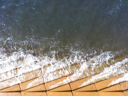 Photo for Aerial view of waves breaking over the concrete steps of a promenade at high tide. - Royalty Free Image