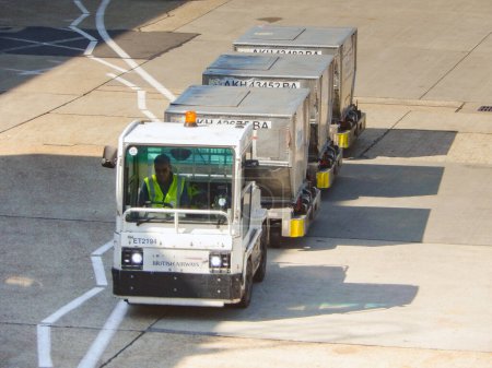 Photo for London, England, UK - 14 June 2023: Small tractor pulling a set of air freight pallets at one of the terminals at Heathrow airport. - Royalty Free Image