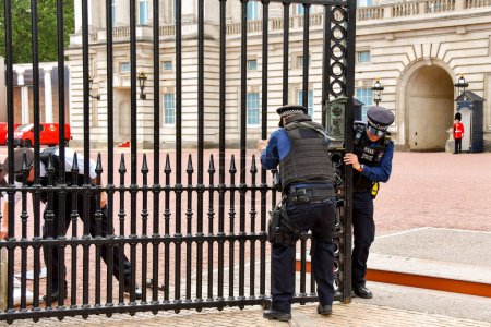 Foto de Londres, Inglaterra, Reino Unido - 27 de junio de 2023: Policías de la Policía Metropolitana intentan cerrar las puertas a la entrada del Palacio de Buckingham en el centro de Londres. - Imagen libre de derechos