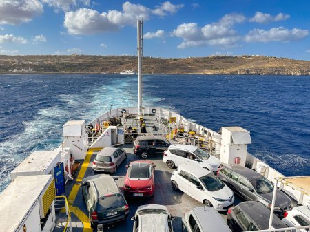 Foto per Gozo, Malta - 5 agosto 2023: Auto sul ponte di un traghetto che parte tra l'isola di Gozo e l'isola principale di Malta.Il traghetto è operato da Gozo Channel Line. - Immagine Royalty Free