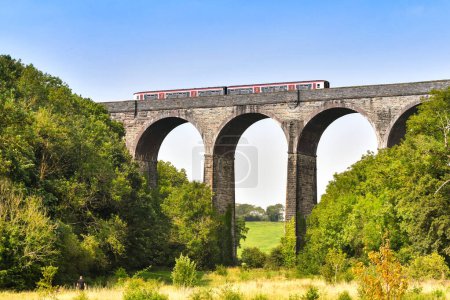 Photo for Barry, Wales - 17 August 2023: Commuter train operated by Transport for Wales crossing the stone viaduct over Porthkerry Country Psrk in south Wales - Royalty Free Image