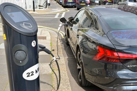 Foto de Londres, Inglaterra, Reino Unido - 22 de agosto de 2023: Coche eléctrico conectado a un punto de recarga de batería rápida en una calle del centro de Londres - Imagen libre de derechos