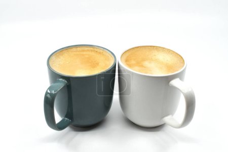 Foto de Dos tazas de café caliente en tazas de colores contrastantes aisladas sobre un fondo blanco liso - Imagen libre de derechos