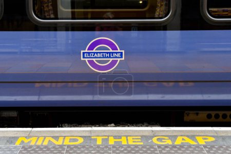 Foto de Londres, Inglaterra, Reino Unido - 27 de junio de 2023: Vista de cerca del lado de un tren en la nueva línea Elizabeth en la estación de tren de Londres Paddington y una señal de advertencia Mind the Gap en el borde de la plataforma - Imagen libre de derechos