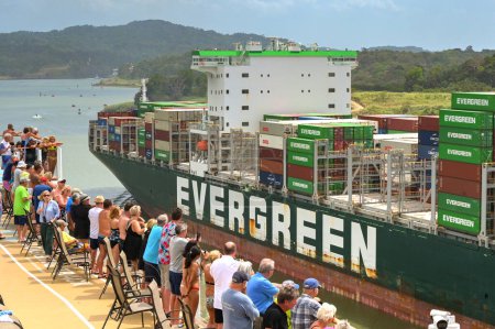 Téléchargez les photos : Canal de Panama, Panama - 23 janvier 2024 : Passagers sur le pont supérieur d'un navire de croisière regardant un porte-conteneurs qui passe - en image libre de droit