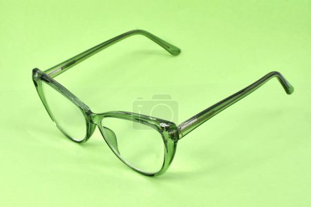 Pair of reding galsses with transparent green frames isolated on a light green background