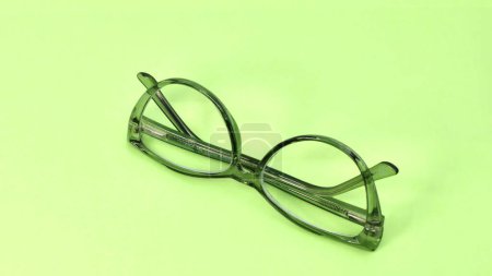 Pair of glasses with a green transparent frame isolated on a plain light green background. Copy space.