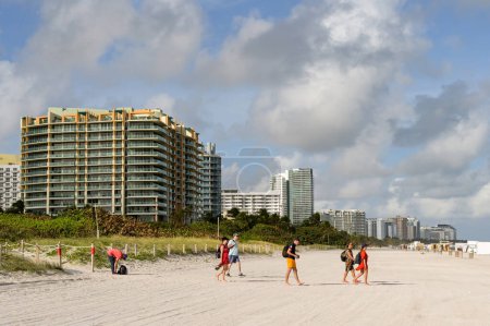 Photo for Miami Beach, Miami, Florida, USA - 1 December 2023: People ewalking acrioss the sand to Miami South Beach. - Royalty Free Image