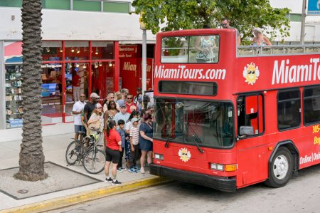 Photo for Miami Beach, Miami, Florida, USA - 1 December 2023: People queuing to get on a tourist hop on hop off sightseeing bus at Miami South Beach. - Royalty Free Image