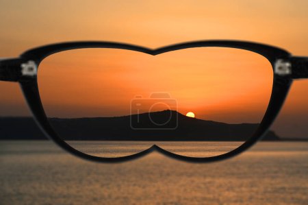 Sonnenuntergang über Bergen und Meer im Fokus, wenn man durch eine Brille mit Gläsern blickt, um Kurzsichtigkeit zu korrigieren. Der Rest der Szene ist verschwommen. Kein Volk. Sehkraft-Konzept.