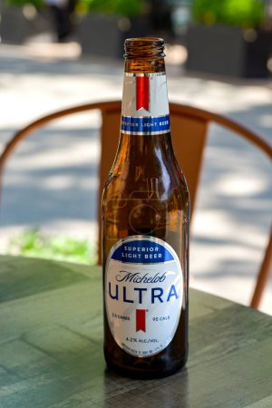 Téléchargez les photos : Alexandria, Virginie - 1er mai 2024 : Bouteille de bière Michelob Ultra légère sur une table dans l'espace repas extérieur d'un restaurant. Pas de peuple. - en image libre de droit