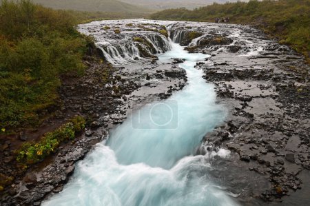 Photo for Distant tourists at Bruarfoss - Bridge Falls - on Icelands Golden Circle route under cloudy autumn sky. - Royalty Free Image