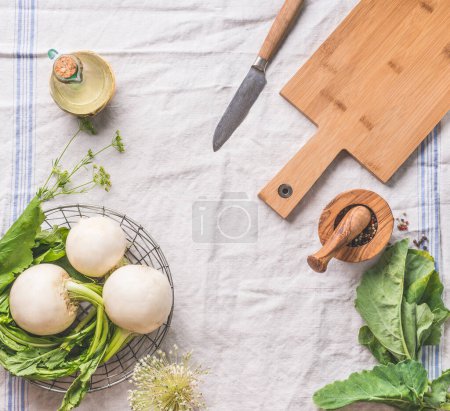 Photo for Food background with raw young turnip  with greens on light kitchen table with cutting board and knife, top view. Healthy vegetarian eating and cooking concept. Copy space for your design - Royalty Free Image