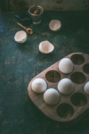 Umweltfreundlicher Eierhalter aus Holz mit rohen Bio-Eiern auf dunklem rustikalem Hintergrund. Aus nächster Nähe. Null Abfall im Haushalt