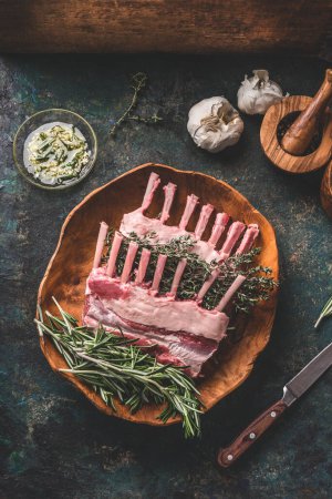 Photo for Raw lamb racks in wooden bowl with herbs and spices on rustic kitchen table , top view. Meat recipes. Grilling preparation.  Organic food.  Cooking - Royalty Free Image