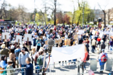 Foto de Unemployment strike, public demonstration or anti government protest. Microphone in focus against unrecognizable crowd. - Imagen libre de derechos