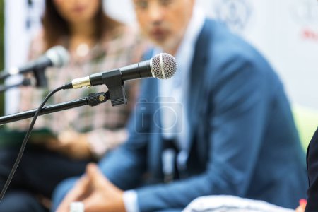 Microphone in focus at round table event or business conference. Public speaking concept.