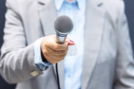 Téléchargez les photos : Une journaliste tient un microphone pendant une interview médiatique - en image libre de droit