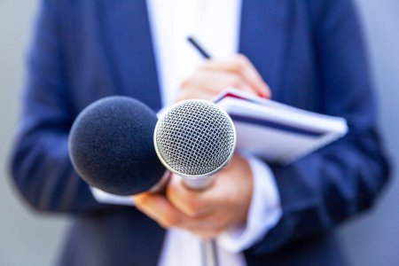 Journaliste féminine lors d'une conférence de presse ou d'un événement médiatique, écrivant des notes, tenant un microphone
