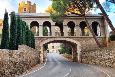Old stone bridge with arch over the road in ancient medieval castle of Peralada in Spain.