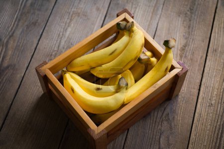 Foto de Ramo de plátanos - plátano sobre fondo de caja de madera, fruta de plátano madura en el suelo - vista superior - Imagen libre de derechos