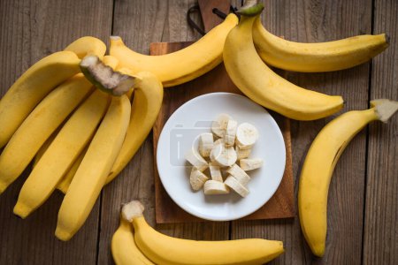 Foto de Bunch of bananas - banana sliced on wooden background, ripe banana peel fruit on floor - Imagen libre de derechos