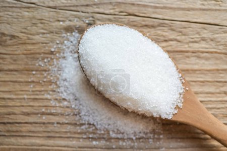 Foto de Azúcar sobre fondo de cuchara de madera, azúcar blanco para alimentos y dulces postre caramelo montón de azúcar dulce granulado cristalino - Imagen libre de derechos