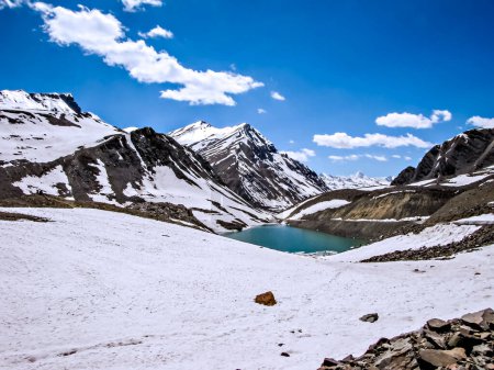 Foto de Montañas cubiertas de nieve con un pequeño lago y nubes blancas en el fondo del cielo azul en camino a Leh. - Imagen libre de derechos