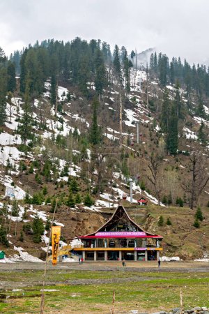 Téléchargez les photos : Solang, Himachal Pradesh, Inde-16 avril 2015 : Bâtiment d'entrée coloré du club de ski et du téléphérique avec des montagnes enneigées en arrière-plan. - en image libre de droit