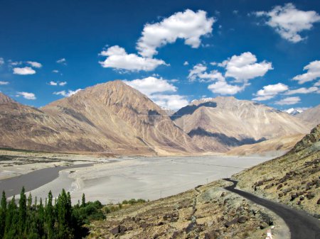 Photo for Mountains and flowing Shyok river with white clouds in blue sky background on way to Diskit in Nubra valley, Leh. - Royalty Free Image