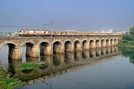 Photo for Pune, Maharashtra, India-November 17th, 2023: Indian Railways conceptual Bharat Gaurav tourist train for showcasing cultural and spiritual richness of India, crossing a bridge with nice reflection in water. - Royalty Free Image