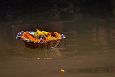 Isoliertes Bild einer schwimmenden Lampe mit Blumen und Kerzen, die dem heiligen Fluss Ganges in Varanasi Ghats dargebracht wird.