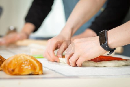 Téléchargez les photos : Gros plan sur les mains des cuisiniers, cuisson boulangerie dans une cuisine lumineuse par deux chefs, mise au point douce sélective. - en image libre de droit