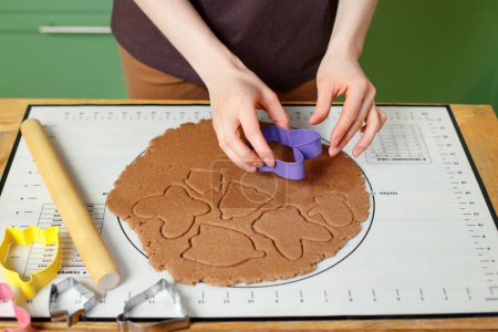 Foto de A woman prepares christmas homemade cookies on a silicone baking mat. - Imagen libre de derechos
